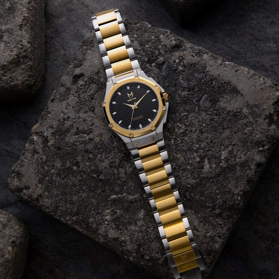 silver and gold watch laying down